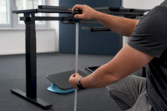 Hands measuring elbow height at desk