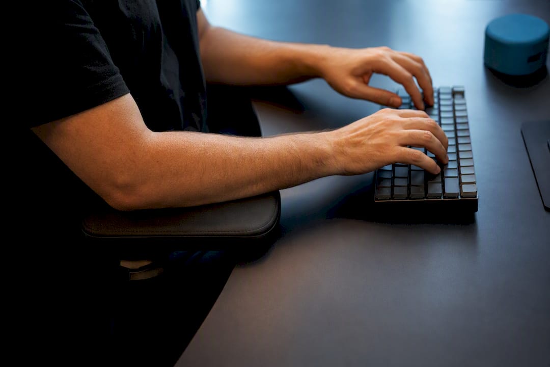 Forearms supported on office chair armrest