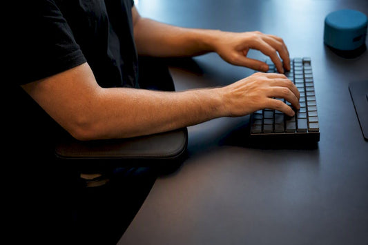 Forearms supported on office chair armrest